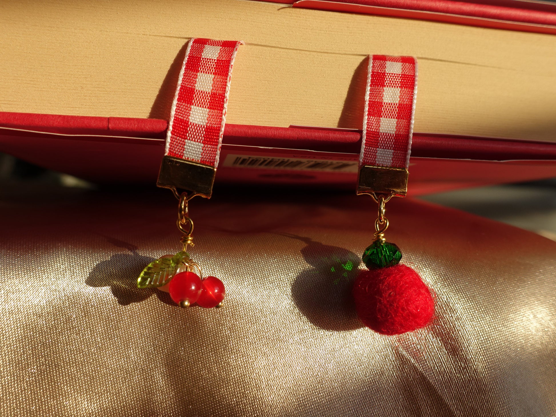 Bookmark with beaded cherries, a tomato,  and green, hanging out of a book